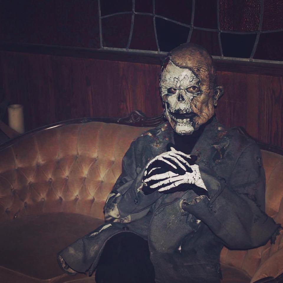 Actor dressed as a skelton sitting on a couch