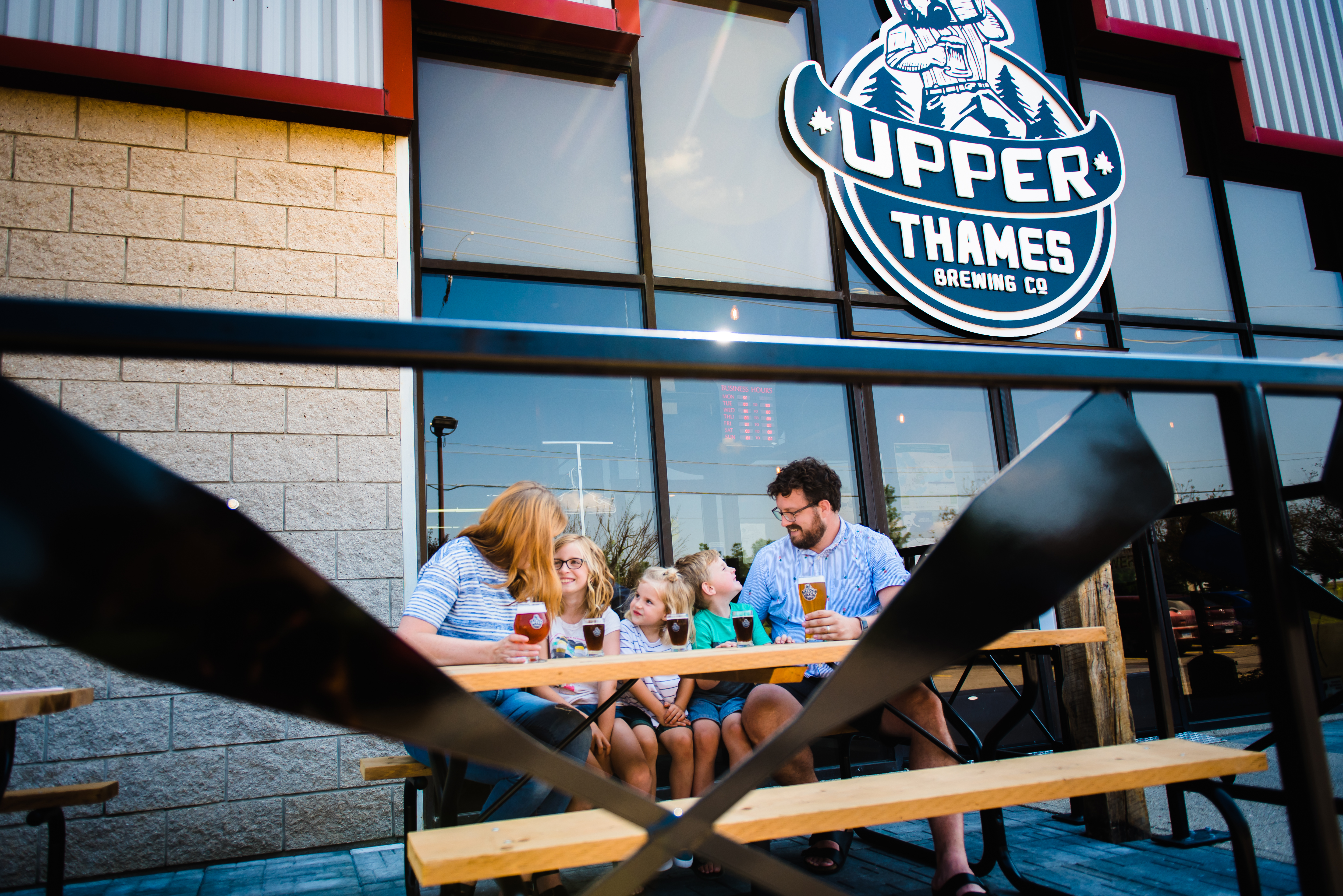 A family sits on the patio at Upper Thames with Beer and Rootbeer